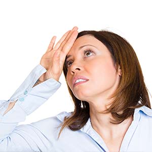A woman with her hand on her head exaggerating the impact of an injury.