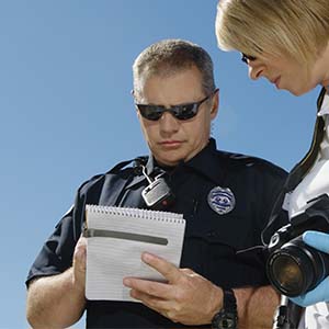 Police officer taking accident report at scene of car accident.